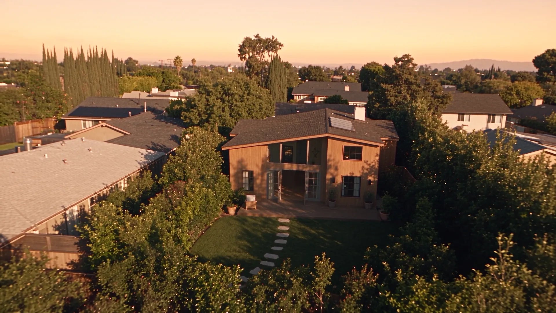 The house from above at golden hour, surrounded by trees